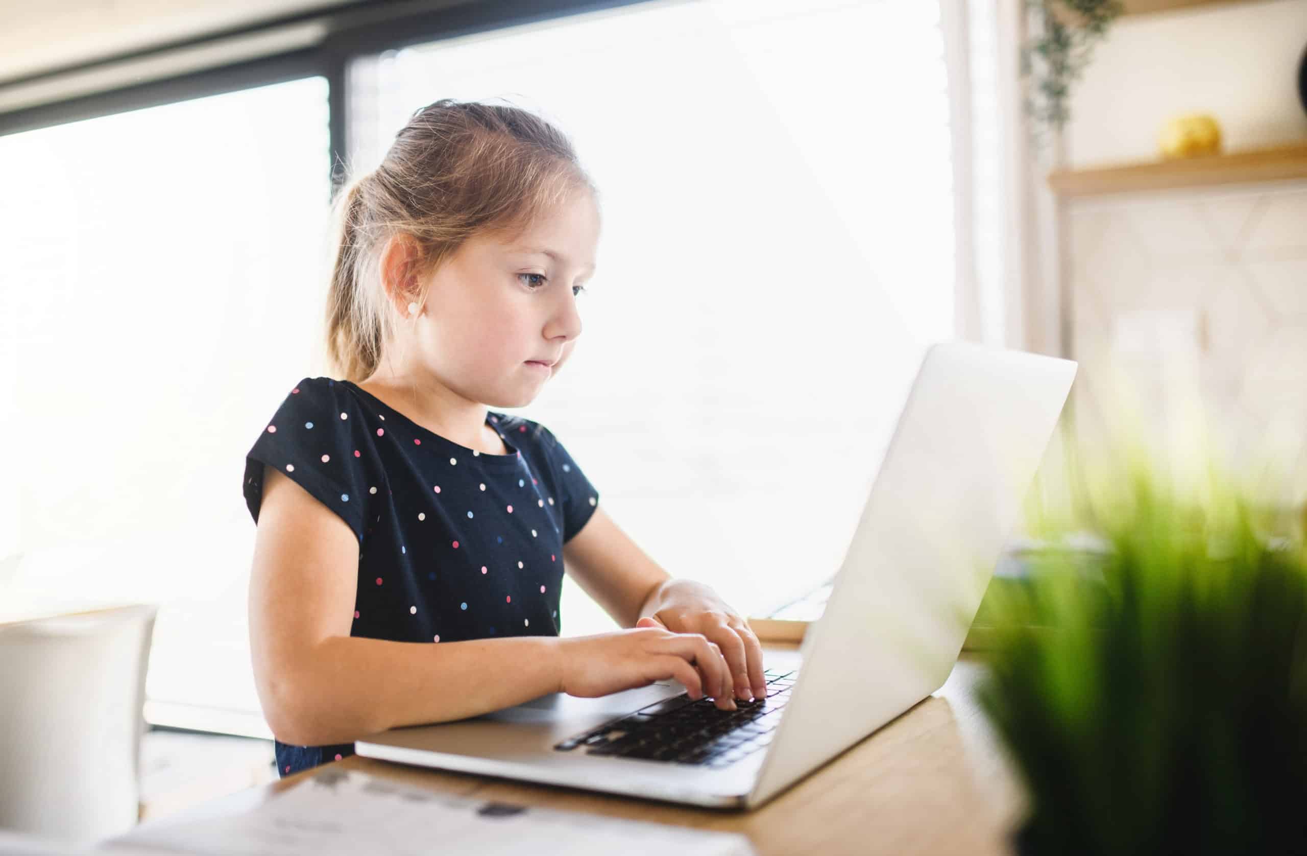 Small girl using laptop indoors at home, Corona virus and quarantine concept.