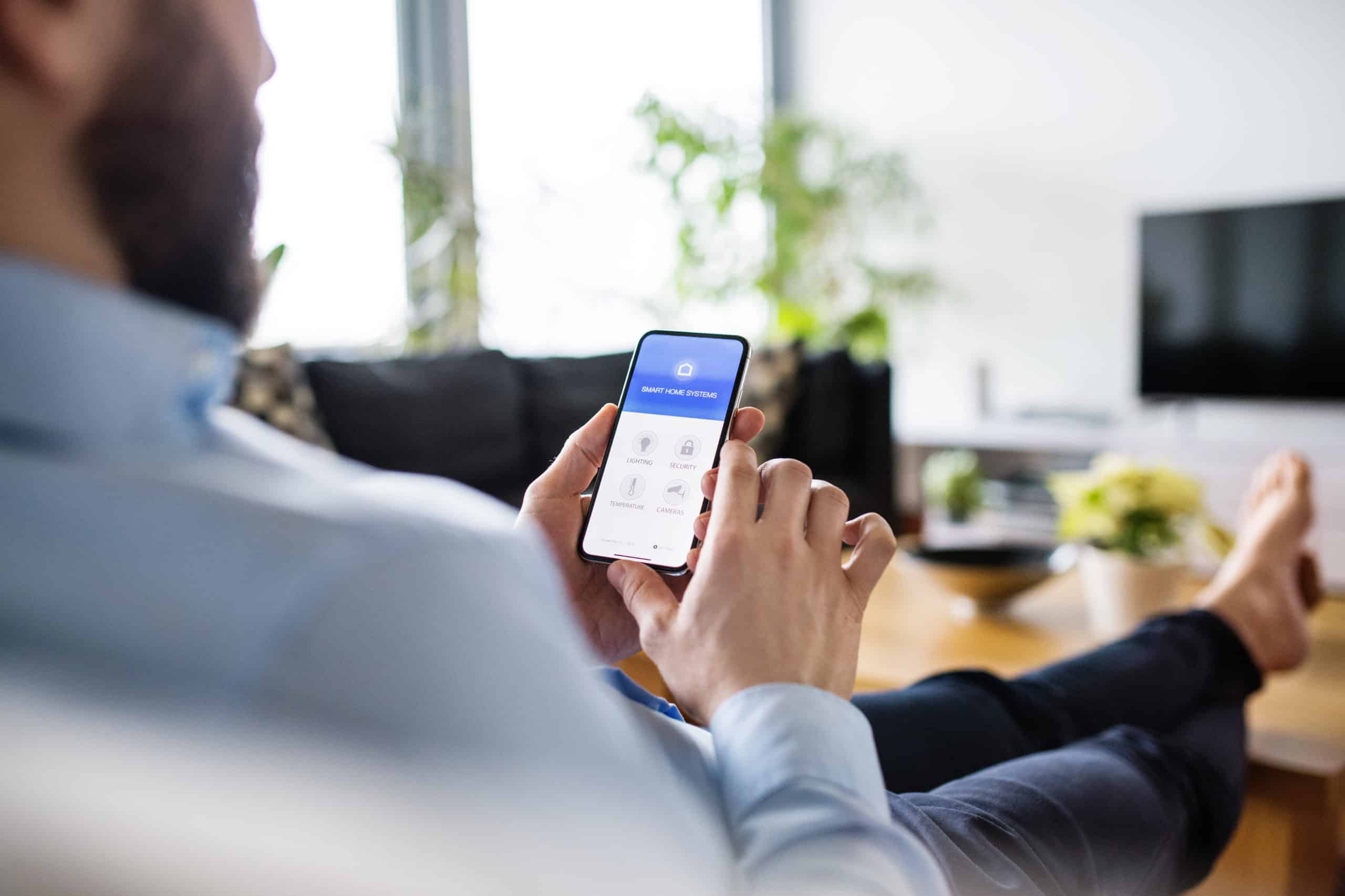 A man holding a smartphone with smart home screen.